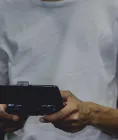 A person holding a physical game controller with a smartphone mounted above it