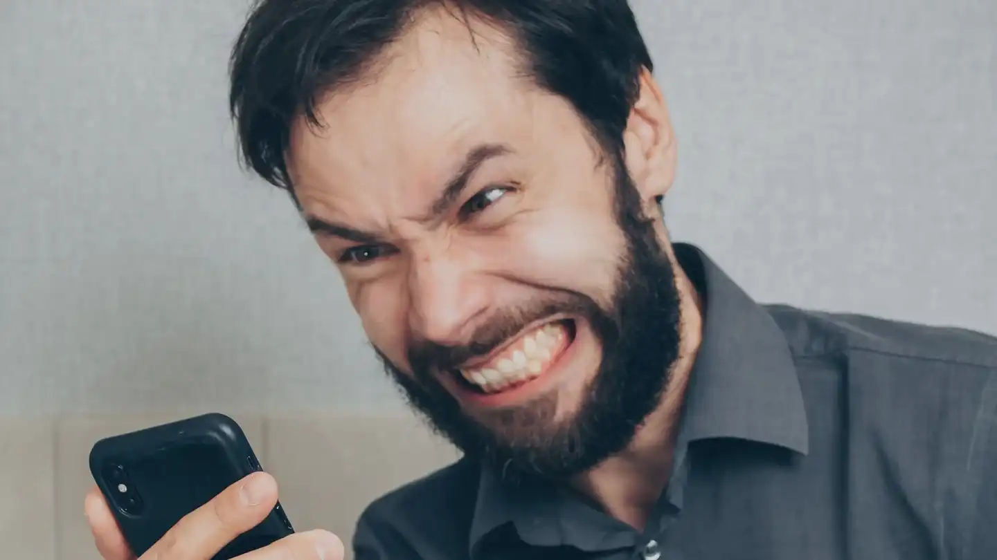A frustrated person looking at a smartphone in his hand