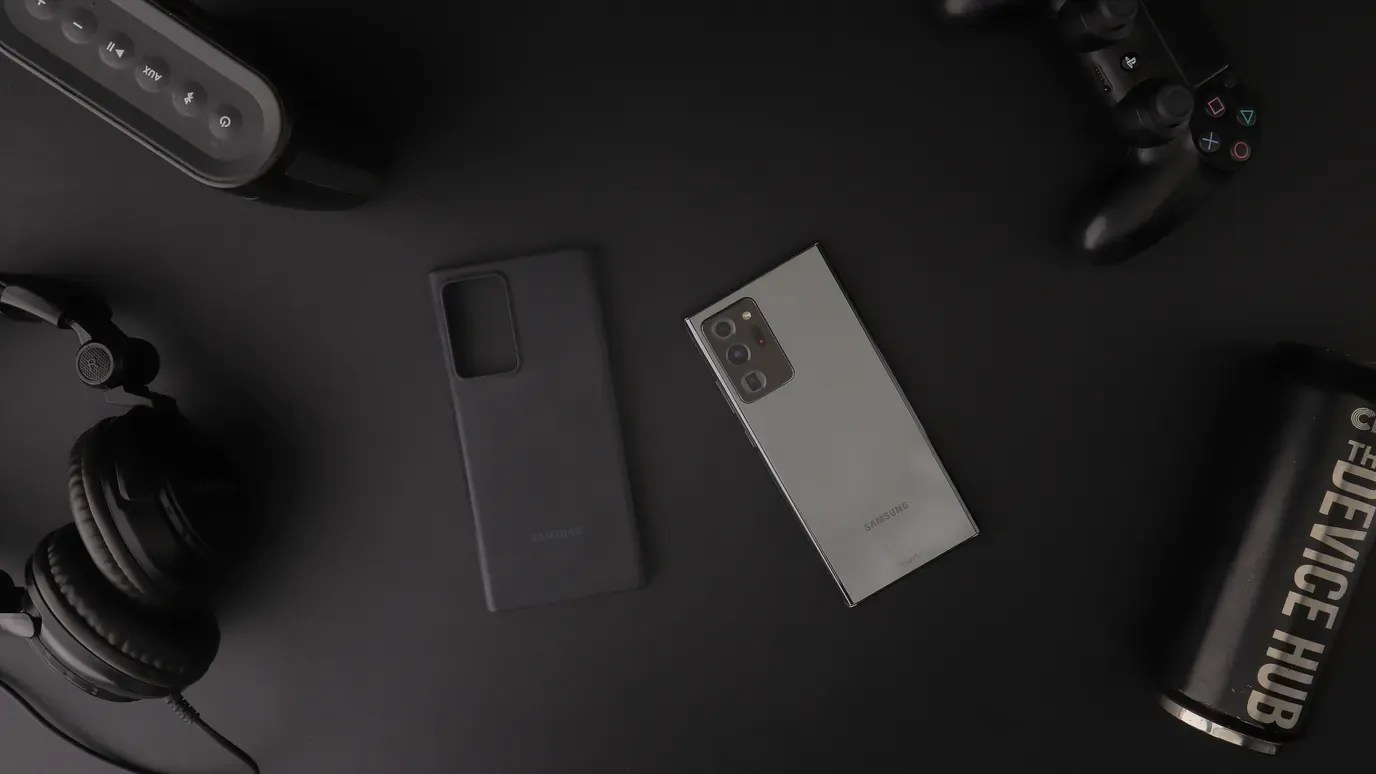 Smartphone, headphones, and game controller arranged on a dark desk