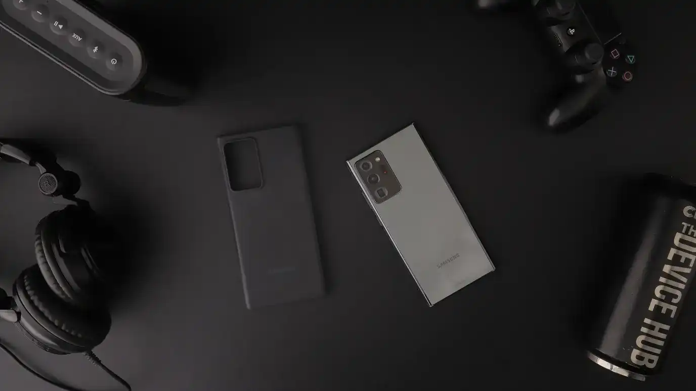Smartphone, headphones, and game controller arranged on a dark desk