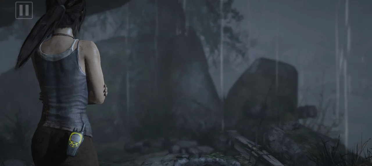 Lara Croft stands in heavy rain near rocky ruins on the island of Yamatai